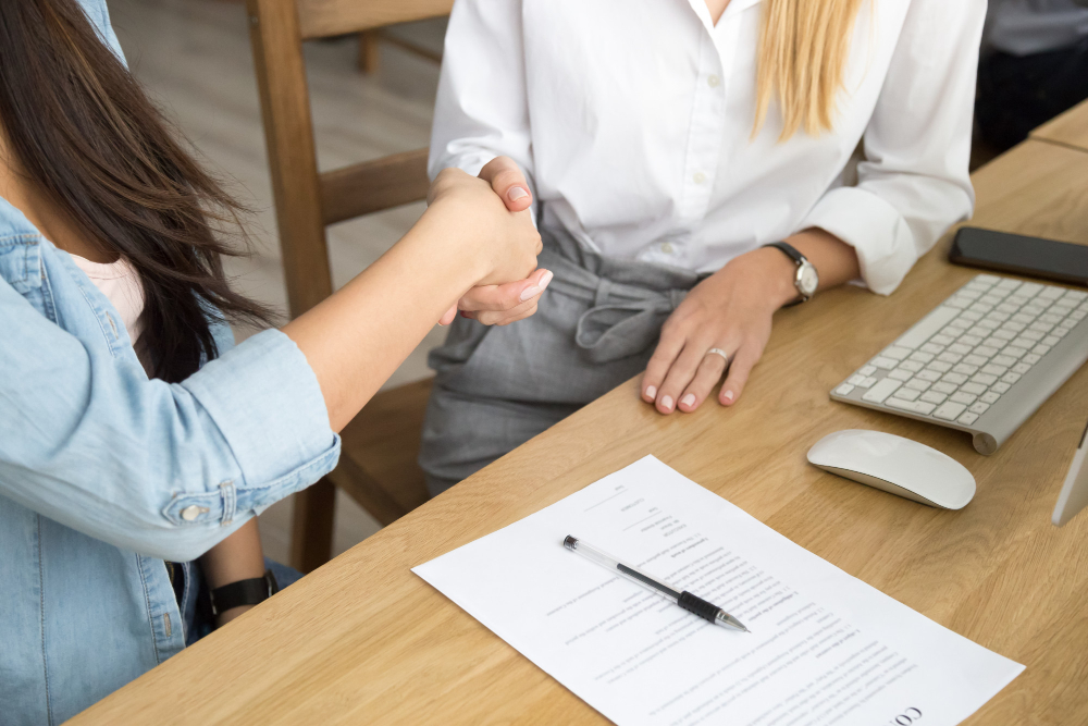 two-women-partners-handshaking-after-signing-business-contract-meeting